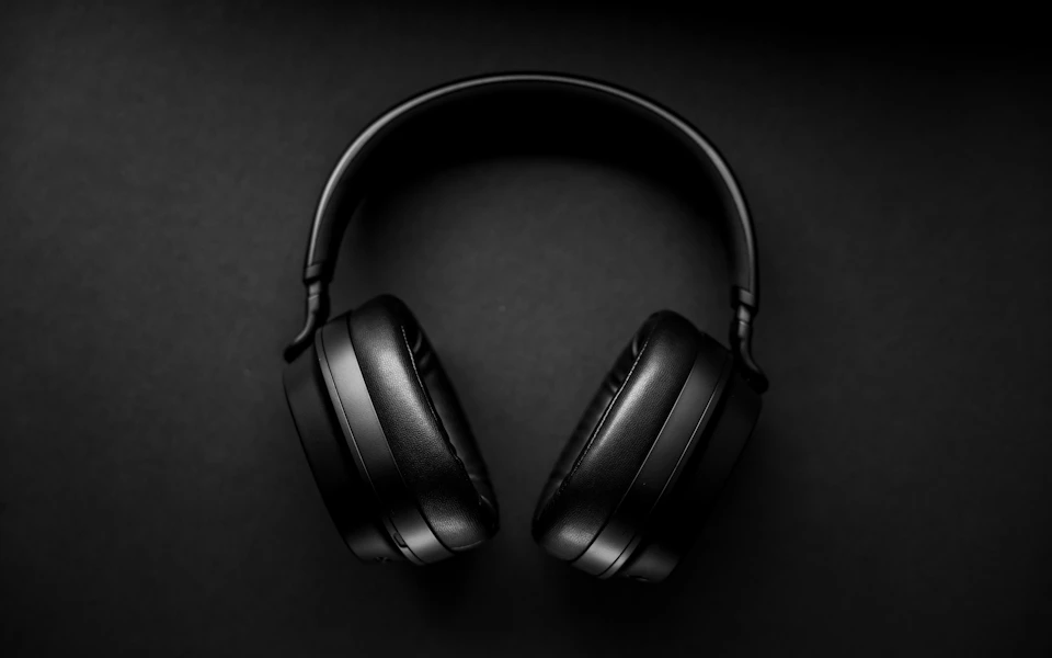 Black over-ear headphones on a dark neutral surface; illustrative category photo.
