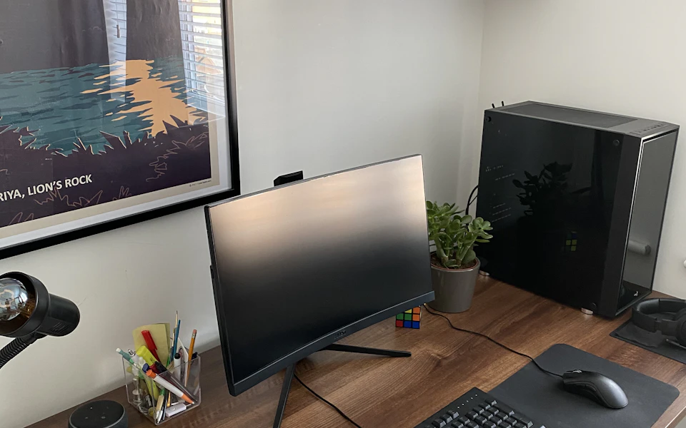 A monitor and keyboard on a wooden desk beside a window; illustrative category photo.
